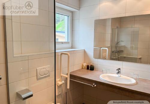 a bathroom with a sink and a glass shower at Sporthotel Bergheim in Sölden