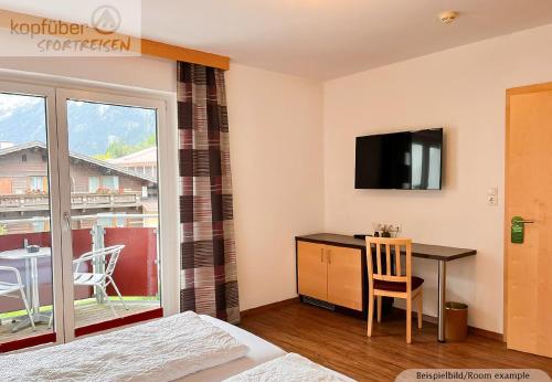 a bedroom with a desk and a tv and a table at Sporthotel Bergheim in Sölden