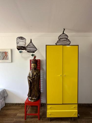 a yellow cabinet with a statue on a red stool at Flor de Limão Hotel Boutique in Coroa Vermelha