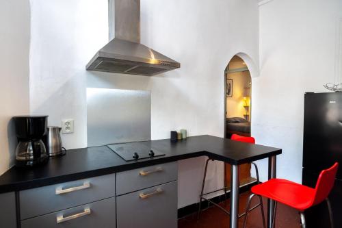 une cuisine avec un comptoir noir et des chaises rouges dans l'établissement Magnifique 2p au coeur du vieux Nice, à Nice