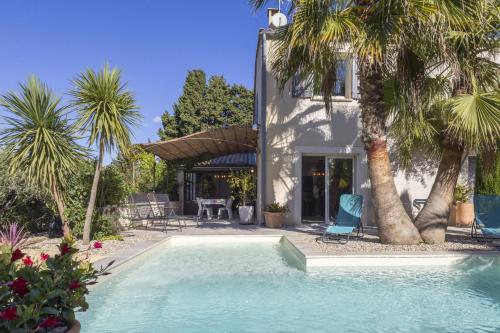 une piscine devant une maison avec des palmiers dans l'établissement Source de Vie, à Noves