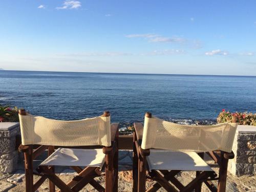 two chairs sitting on a wall overlooking the ocean at Porto Sisi Hotel Apartments in Sissi