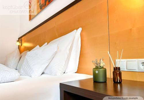 a bed with white pillows and a wooden headboard at Sporthotel Bergheim in Sölden