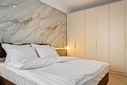 1 Schlafzimmer mit einem weißen Bett und einer Marmorwand in der Unterkunft Apartament Luxury Cortina North Residence Pipera in Voluntari