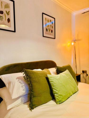 a bed with green and white pillows on it at The Secret Garden Retreat With Hot Tub in Manchester