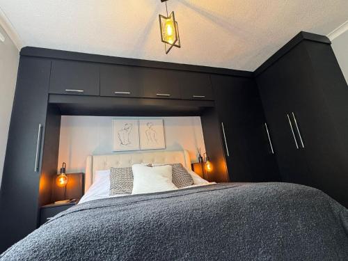 a bedroom with a large bed with black cabinets at The Secret Garden Retreat With Hot Tub in Manchester