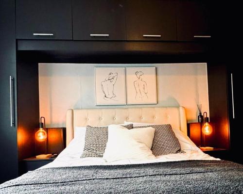 a bedroom with a large bed with two pictures above it at The Secret Garden Retreat With Hot Tub in Manchester