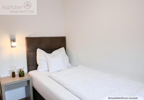 a bed with white sheets and pillows in a room at Sporthotel Bergheim in Sölden
