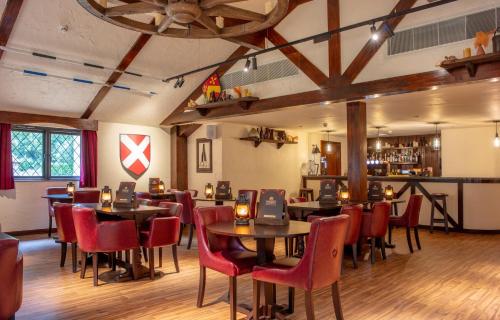 a restaurant with tables and chairs and a bar at Warwick Castle Hotel & Knight's Village in Warwick