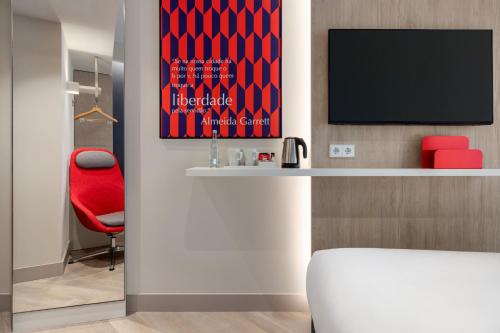 a room with a red chair and a television at Holiday Inn Express Porto - Boavista by IHG in Porto