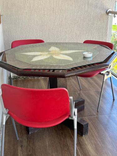 a table with a red chair and a glass top at Flor de Limão Hotel Boutique in Coroa Vermelha