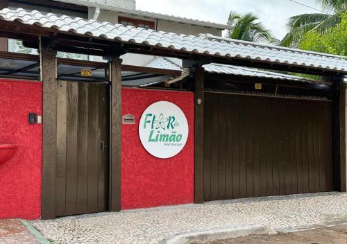 a red building with a gate with a sign on it at Flor de Limão Hotel Boutique in Coroa Vermelha