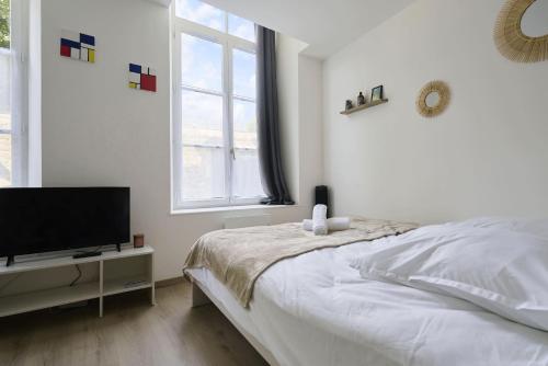 une chambre blanche avec un lit et une télévision à écran plat dans l'établissement Au Cœur des Remparts - Studio 2p, vieille ville BSM, à Boulogne-sur-Mer