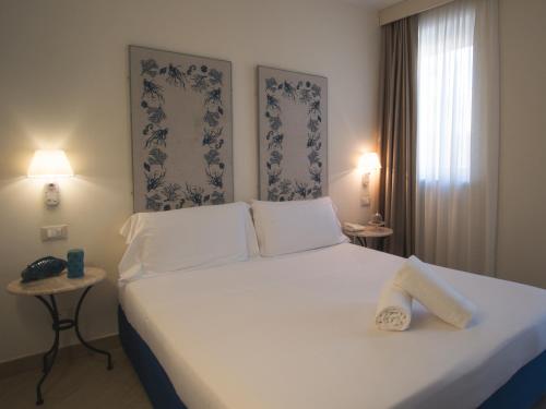 a bedroom with a large white bed with two pillows at Hotel San Pietro Palace in Finale Ligure