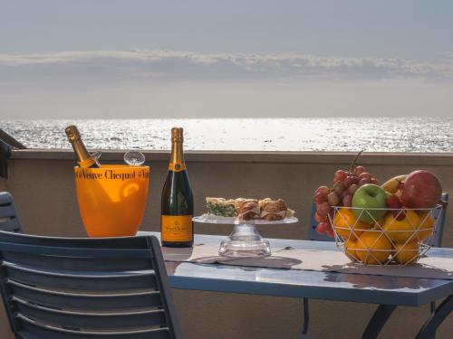 a table with a bowl of fruit and two bottles of wine at Hotel San Pietro Palace in Finale Ligure