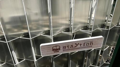 a sign is hanging on a wall with silver tiles at The Staytion Hotel at Sukhumvit in Amphoe Phra Khanong