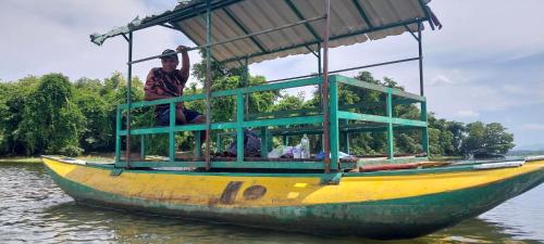 a man sitting on a boat in the water at Hotel white house mahiyanganaya in Mahiyangana