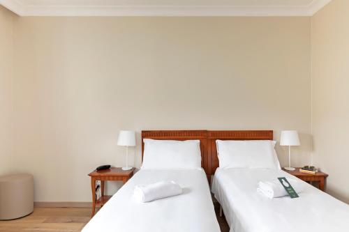 a bedroom with two beds with white sheets and lamps at B&B Hotel Affi - Lago di Garda in Affi
