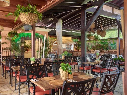 a restaurant with wooden tables and chairs and plants at Green Garden Eco Resort in Playa de las Americas