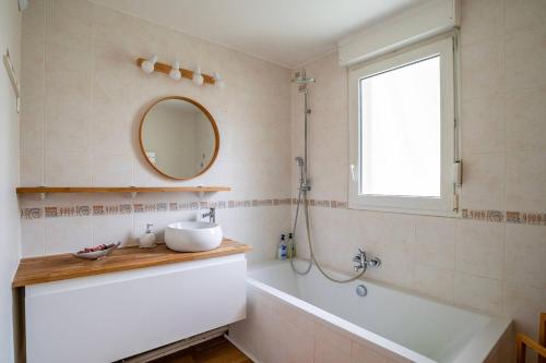a bathroom with a tub and a sink and a mirror at Glacière - 15 min Marché de Noël - Balcon in Schiltigheim