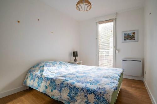 a bedroom with a bed with a blue and white blanket at Glacière - 15 min Marché de Noël - Balcon in Schiltigheim