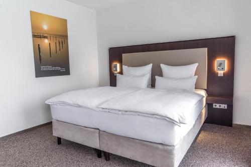 a bedroom with a large bed with white sheets at Fontane Hotel in Schorfheide