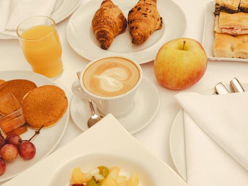 a table with plates of breakfast foods and a cup of coffee at Hotel San Pietro Palace in Finale Ligure