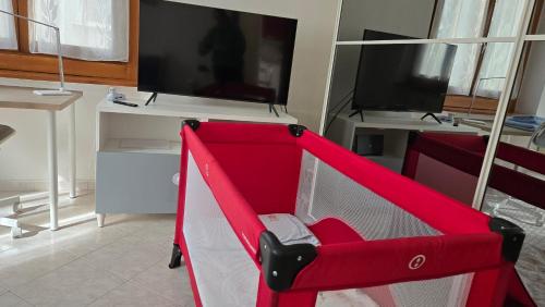 a red chair in front of a tv in a room at Grazioso bilocale a Legnano. in Legnano