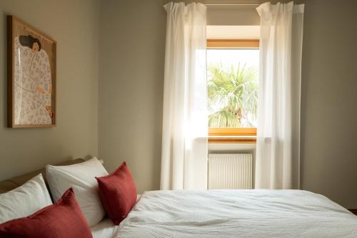 a bed with red pillows in a bedroom with a window at 240qm Luxus Apartment - Natur & Wandern zw Bozen und Meran in Nalles