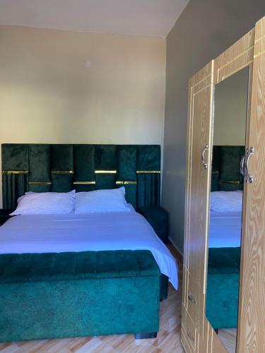 a bedroom with a large bed and a mirror at HA LUXURY STUDIO SUITE 2 buziga in Gaba