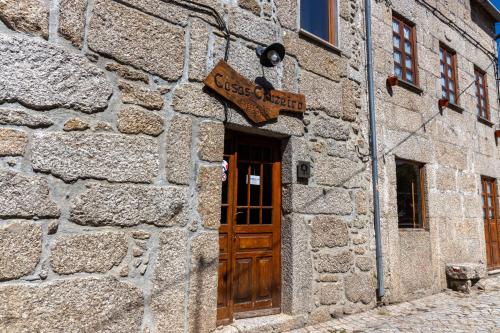 a stone building with a door and a sign on it at Casas do Cruzeiro in Sabugueiro
