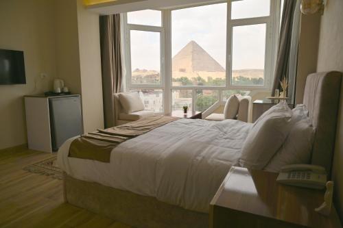 a hotel room with a large bed and a view of the pyramid at Pyramids Wonders Hotel in Cairo