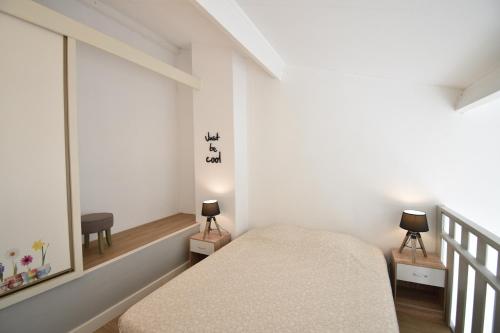 une petite chambre avec un lit et une fenêtre dans l'établissement Point d'or B - Hossegor agréable studio en duplex situé dans une résidence avec piscine en bord de plage, à Soorts-Hossegor