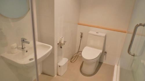 a white bathroom with a toilet and a sink at The Staytion Hotel at Sukhumvit in Amphoe Phra Khanong