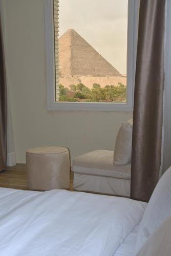 a bedroom with a view of the pyramids from a window at Pyramids Wonders Hotel in Cairo