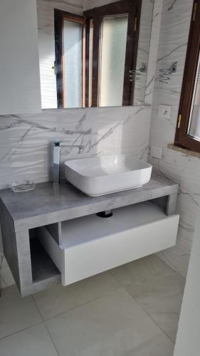a white bathroom with a sink and a mirror at La casa dell'artista in Ardea
