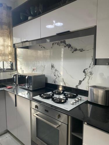 a kitchen with a stove and a microwave at HA LUXURY TWO BEDROOMED Munyonyo in Gaba