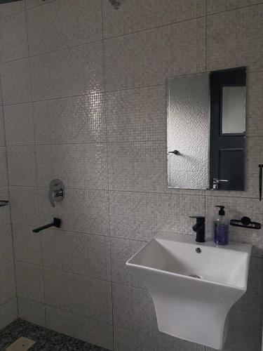 a white bathroom with a sink and a mirror at HA LUXURY TWO BEDROOMED Munyonyo in Gaba
