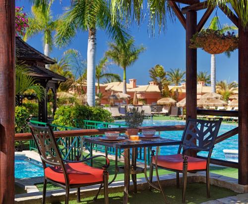 a table and chairs in front of a pool at Green Garden Eco Resort in Playa de las Americas