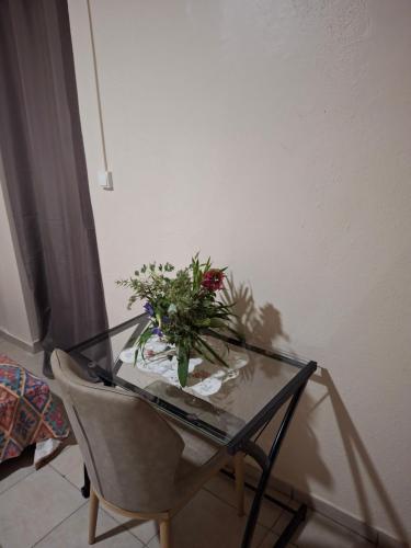 a glass table with a vase of flowers and a chair at Botolava sud in Bouéni
