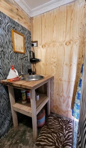 a bathroom with a sink and a wooden wall at Patience Airport cottages in Boma la Ngombe