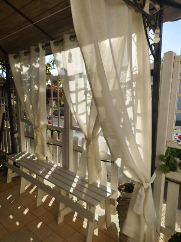a white bench on a porch with white curtains at Trullo Di Tagaro in Locorotondo