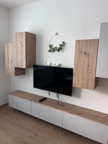 a flat screen tv on a wall with wooden cabinets at Netflix & WiFi FREE Dvojizbový byt blízko centra - 24h self check-in in Banská Bystrica