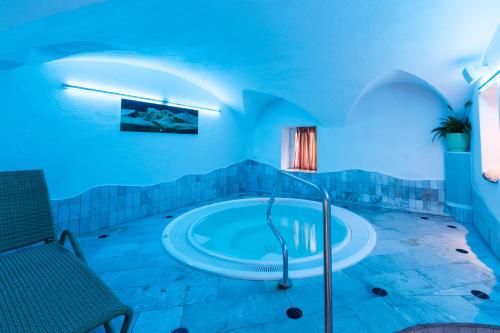 un ampio bagno con vasca in una stanza con illuminazione blu di Hotel Goldene Rose a Monguelfo