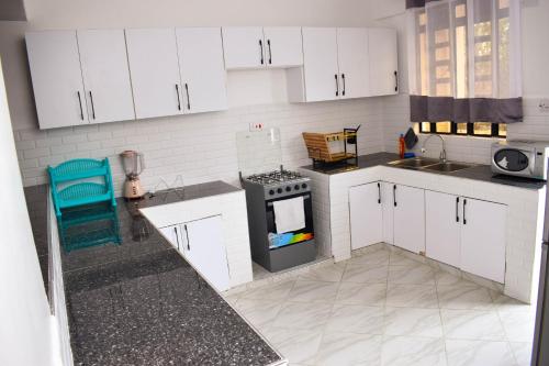 a kitchen with white cabinets and a stove at Mzinyi Homes in Voi
