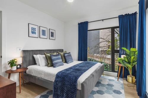 a bedroom with a bed with blue curtains and a window at Luxury in The Gulch with Patio Pool Walk to Broadway in Nashville