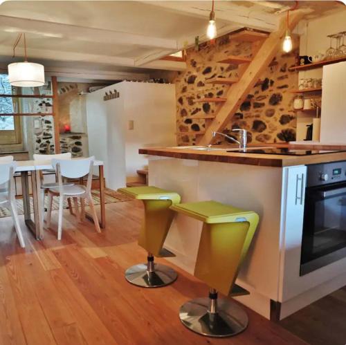 une cuisine avec un évier et un comptoir avec des tabourets dans l'établissement La Maison du Fenil de Tende Vallee des Merveilles, à Tende