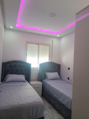 a room with two beds and a pink light at plage Taït club omeGa in Andalouciene