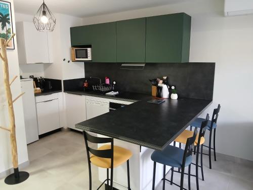 une cuisine avec des placards verts et un comptoir noir dans l'établissement Superbe appartement neuf, à Six-Fours-les-Plages