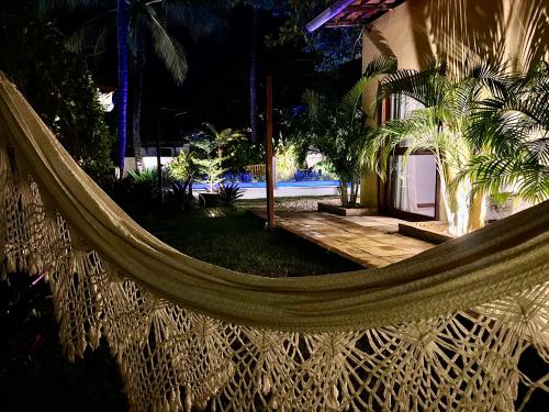 a hammock in front of a house with a pool at Villa Biju in Jericoacoara